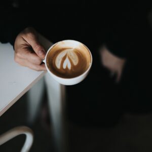 persoon met kop cappuccino met latte art in handen